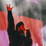 The Weeknd con la mano en alto durante un concierto de su gira