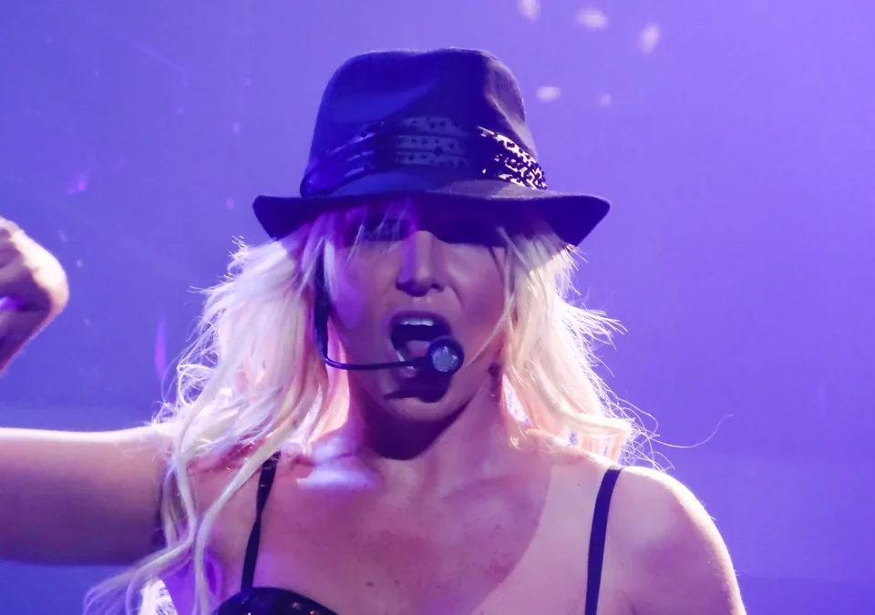 Britney Spears cantando con sombrero negro y micrófono de diadema