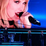 Taylor Swift canta en un concierto con su rostro en la pantalla gigante del escenario