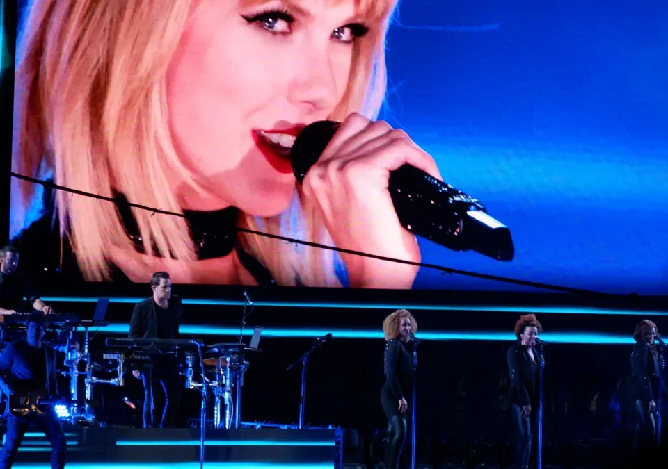 Taylor Swift canta en un concierto con su rostro en la pantalla gigante del escenario