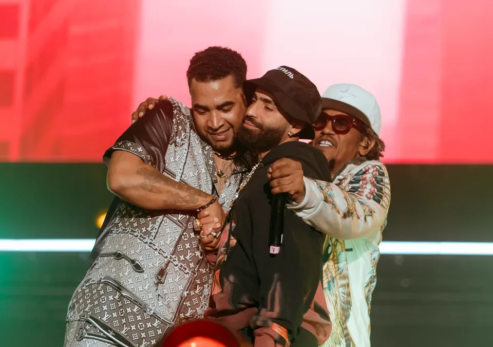Arcángel, con gorra, abrazado a Don Omar y Tego Calderón sobre un escenario