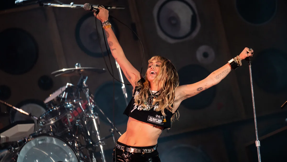 Miley Cyrus con los brazos abiertos sobre el escenario