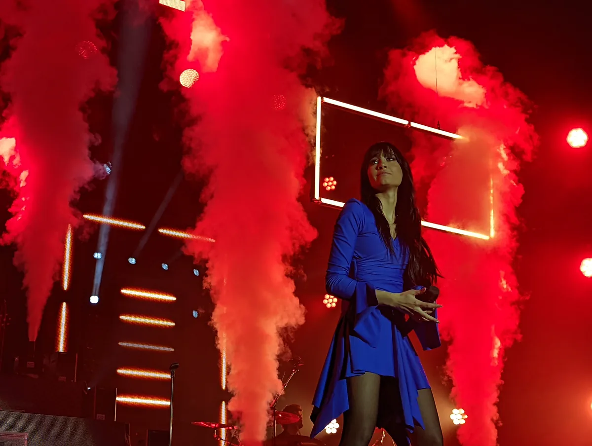 Aitana sobre el escenario entre columnas de humo rojo