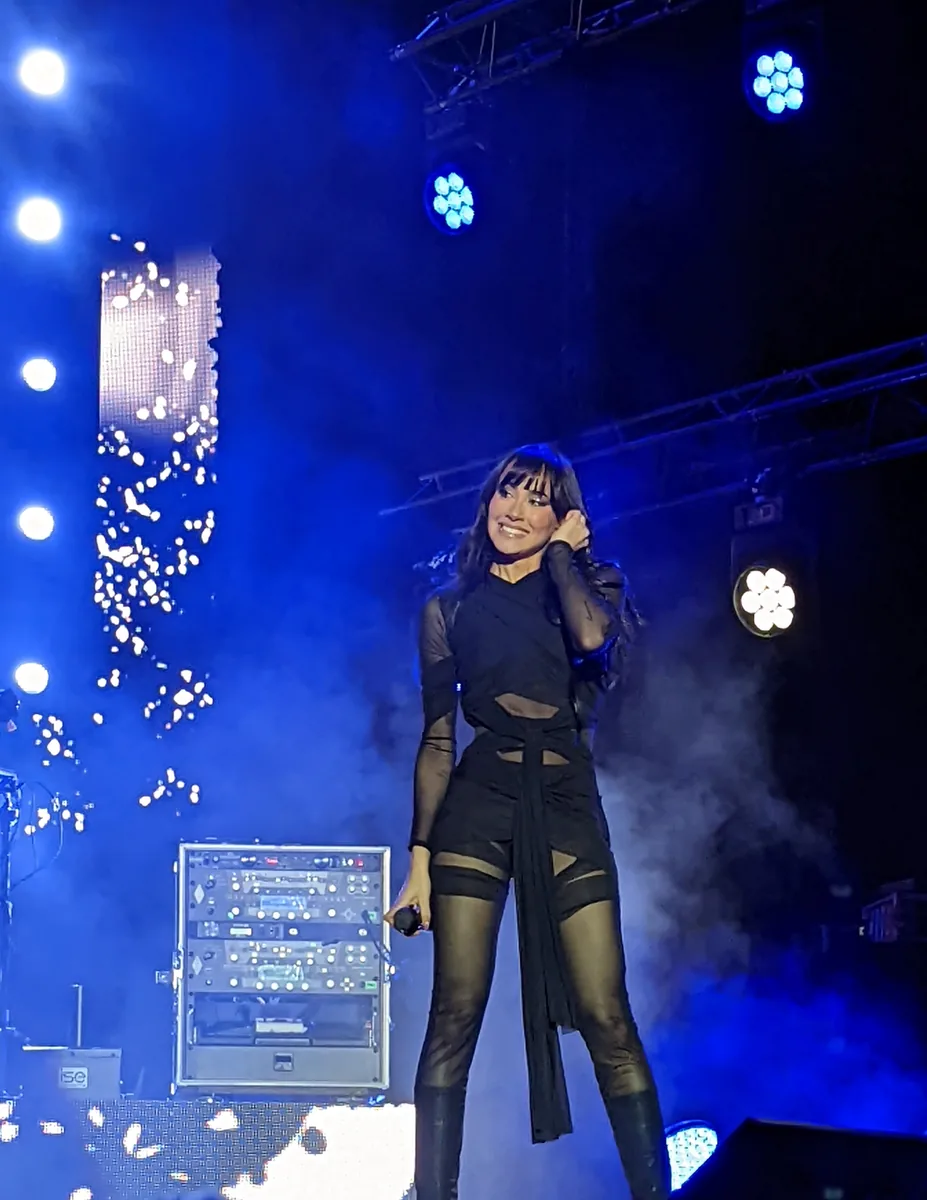 Aitana sonríe en el escenario iluminada de azul