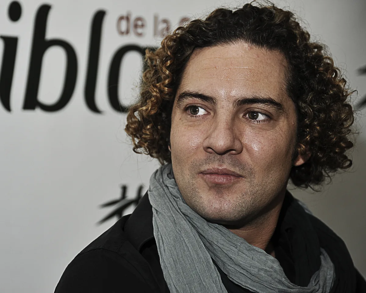 Primer plano de David Bisbal con el pelo rizado y un pañuelo gris