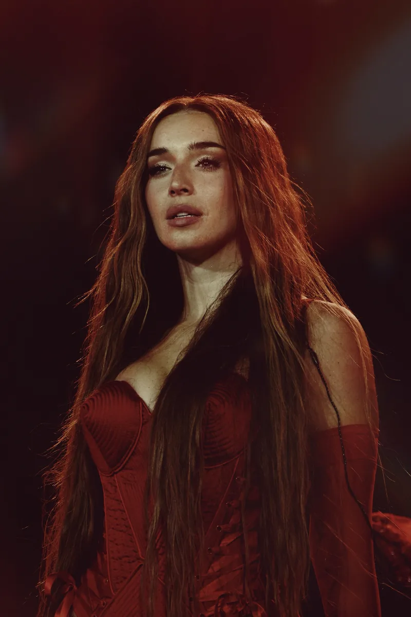 Lola Índigo cantando en un concierto con un corsé rojo