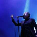 Iván Ferreiro cantando ante el micrófono bajo una luz azul