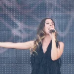 Leire Martínez cantando con el brazo extendido sobre un escenario