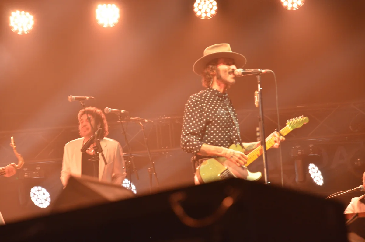 Primer plano de Leiva con sombrero cantando ante el micrófono