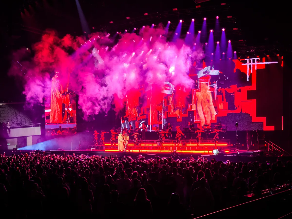 Escenario de un concierto de Maluma con humo rosa y público