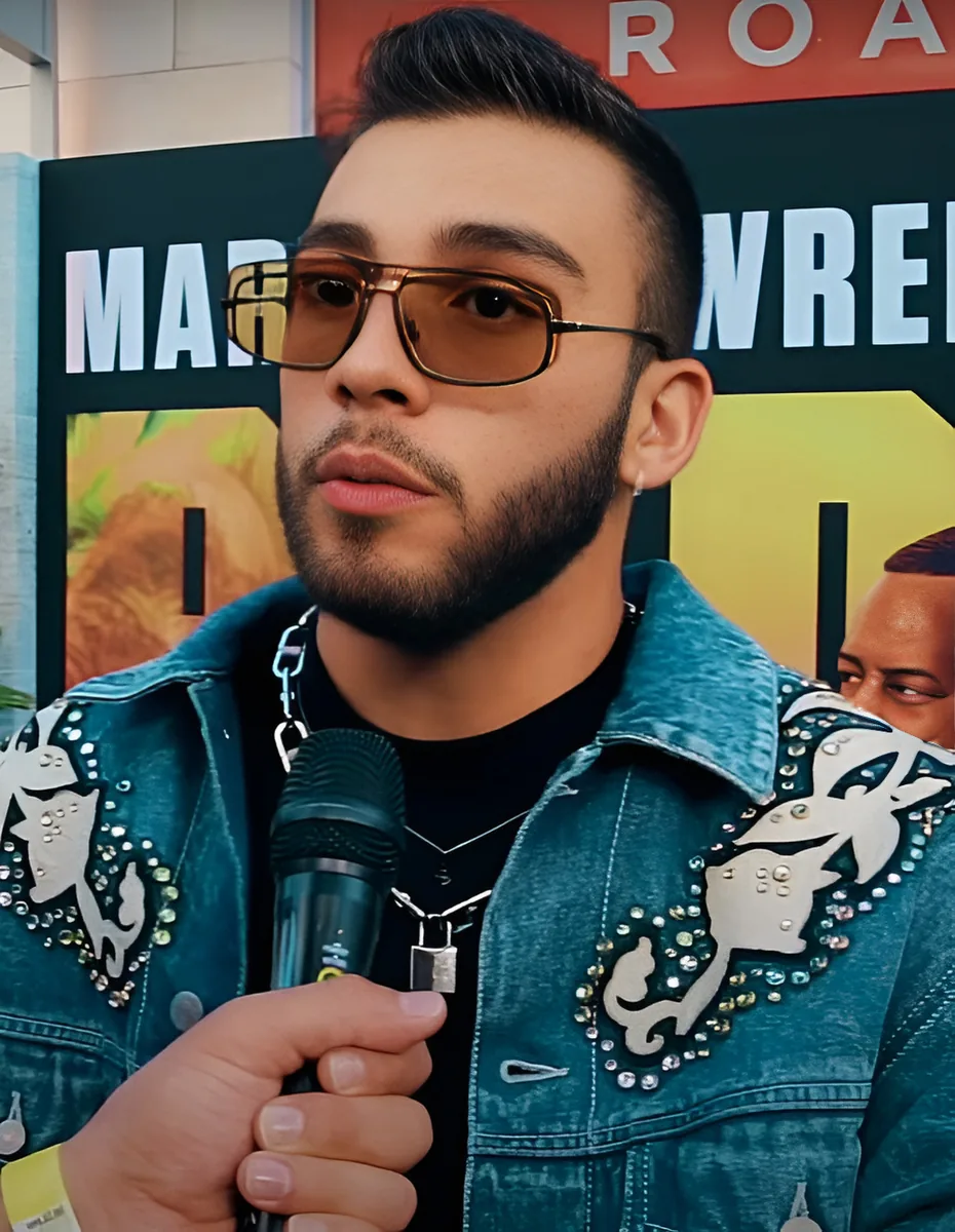 Manuel Turizo con gafas de sol y chaqueta vaquera atiende a la prensa con un micrófono