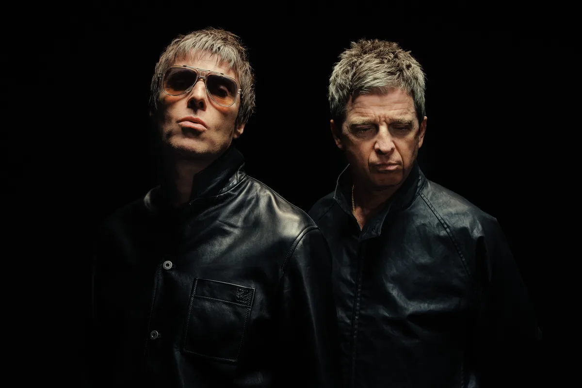 Liam y Noel Gallagher, de Oasis, con chaquetas de cuero negras sobre fondo oscuro