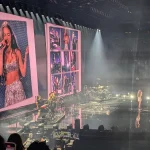Olivia Rodrigo en el escenario durante un concierto, con su imagen en las pantallas