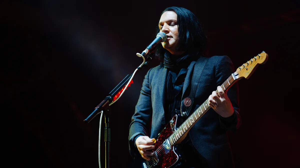 El cantante de Placebo, cantando con una guitarra en un concierto