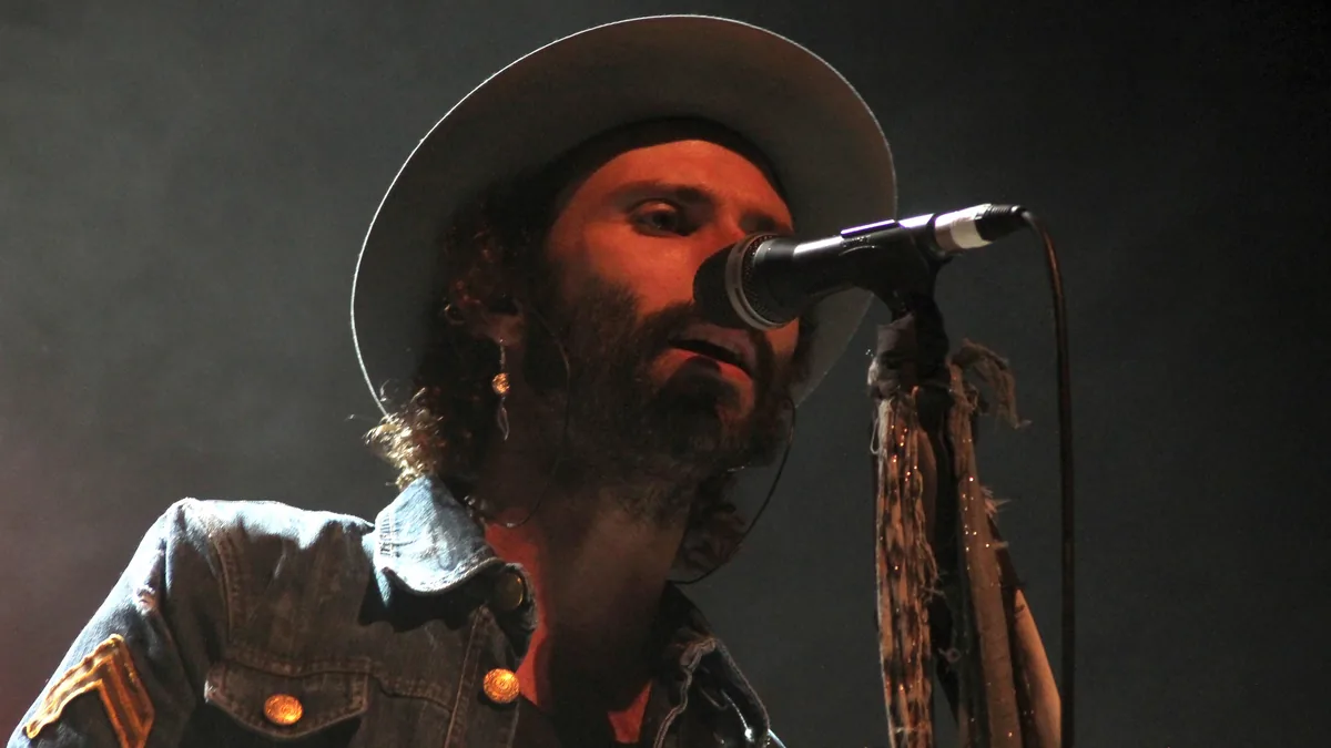 Leiva cantando con sombrero ante el micrófono en un concierto