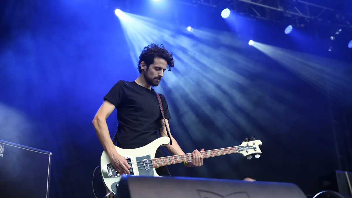 El bajista de Viva Suecia tocando bajo focos azules en un festival