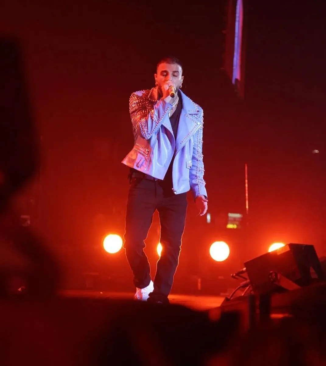 Rauw Alejandro cantando sobre el escenario con luces rojas