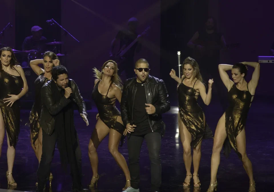 Cali y El Dandee cantando en directo con bailarinas en el escenario
