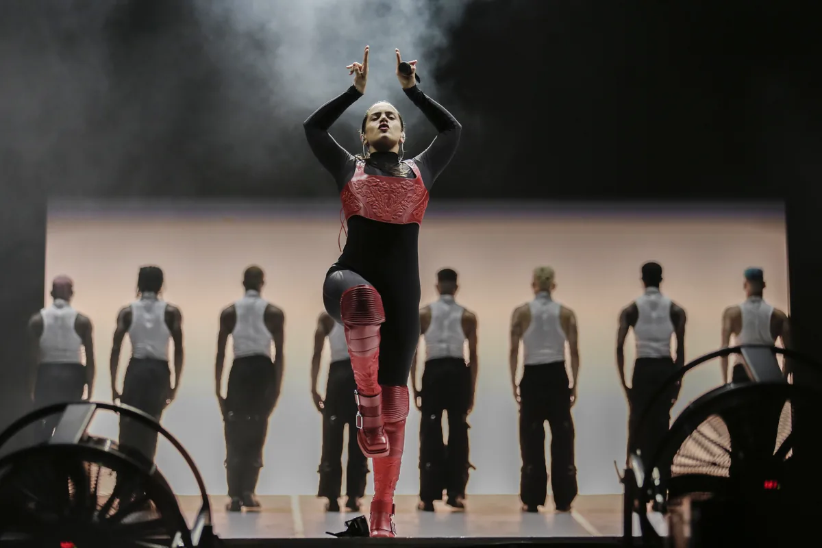Rosalía con los brazos en alto rodeada de bailarines en el escenario