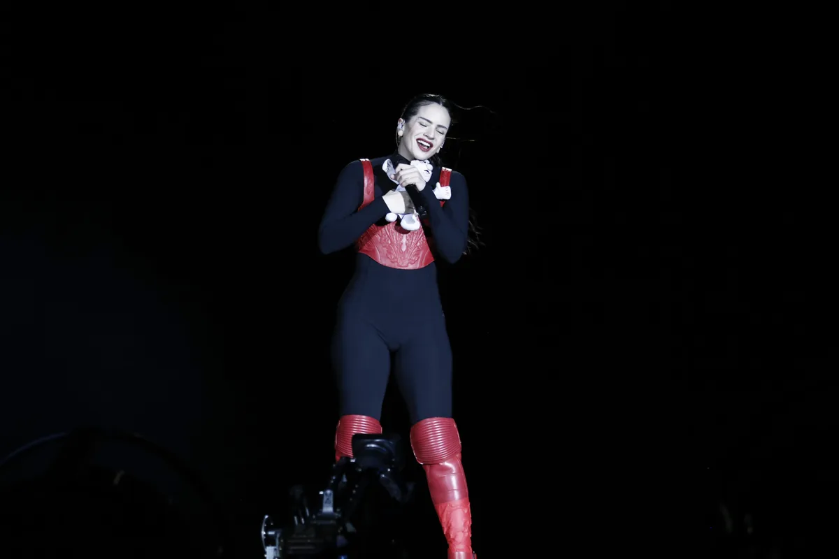 Rosalía sobre el escenario con un traje negro y rojo