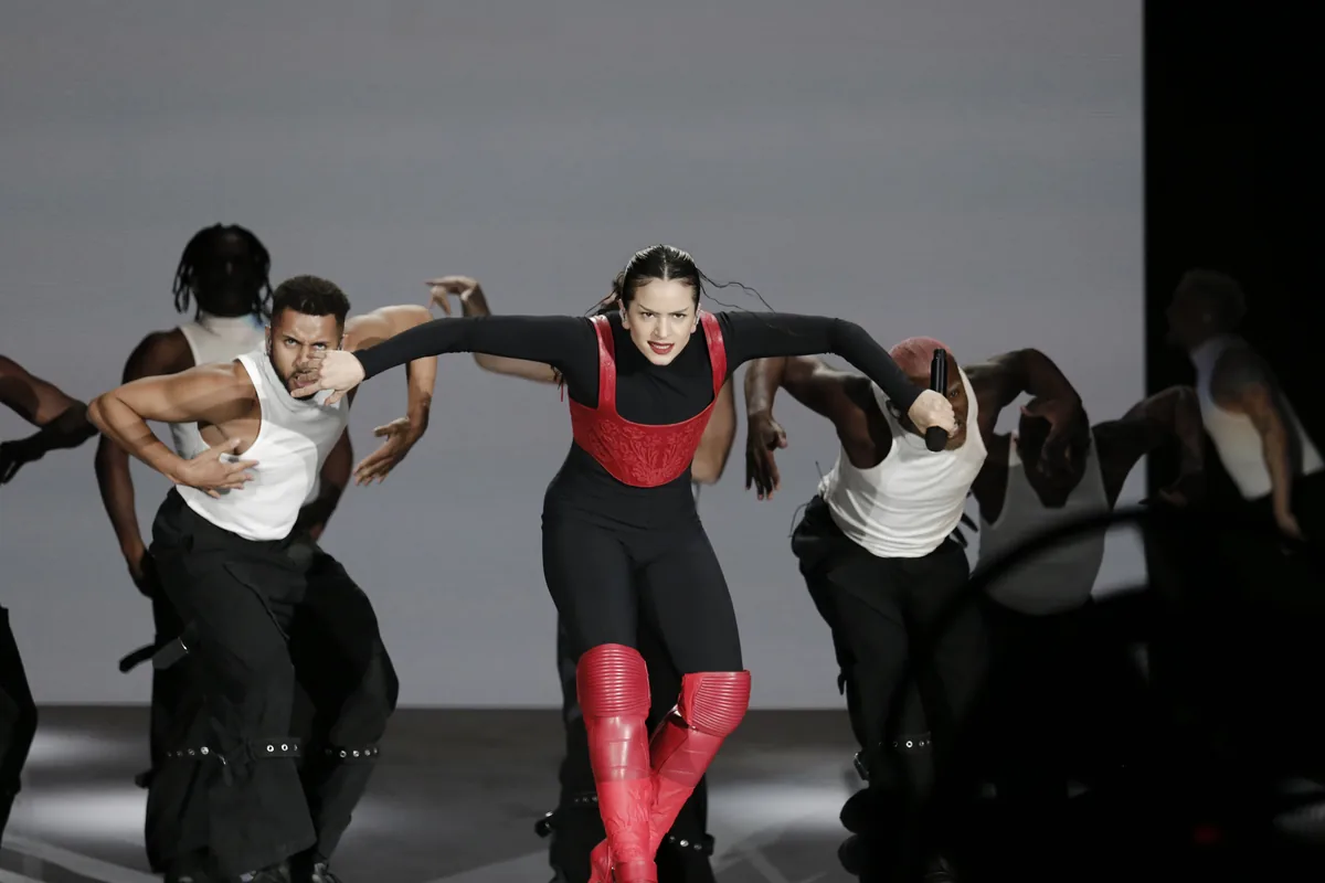 Rosalía baila sobre el escenario con sus bailarines, corsé rojo y botas rojas