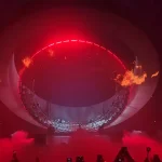 Escenario circular de Swedish House Mafia iluminado en rojo con llamas