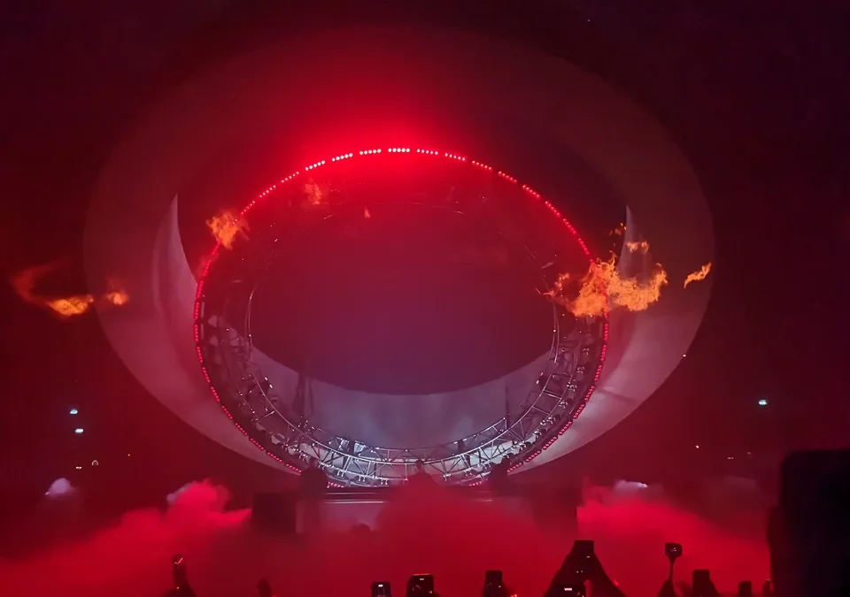 Escenario circular de Swedish House Mafia iluminado en rojo con llamas