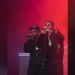 ROA y Anuel AA cantan juntos sobre un escenario iluminado en rojo